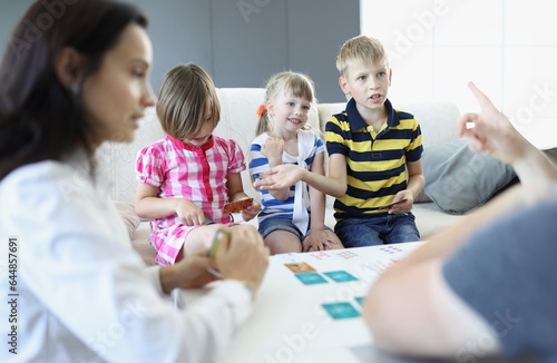 Adults and children sit around a table on which playing cards are located boy argues and discusses the rules with an adult. Game ways to solve children's conflicts concept