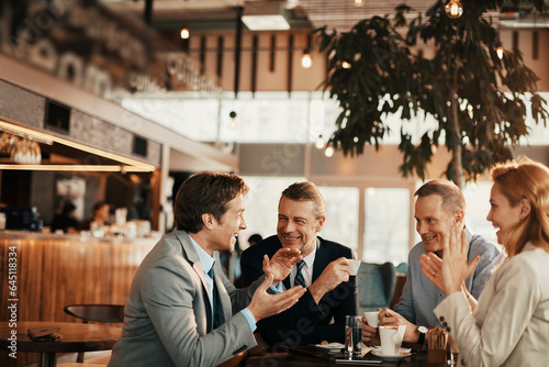 Group of middle aged business coworkers having a meeting over coffee in a cafe decorated for christmas and the new year holidays