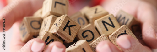 Woman hands hold heap of wooden cubes with letters close up.