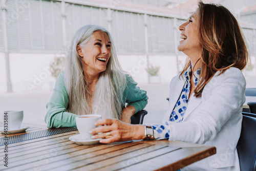 Beautiful senior women meeting outdoors in the city - Two mature female adults friends bonding and having fun while shopping outdoors