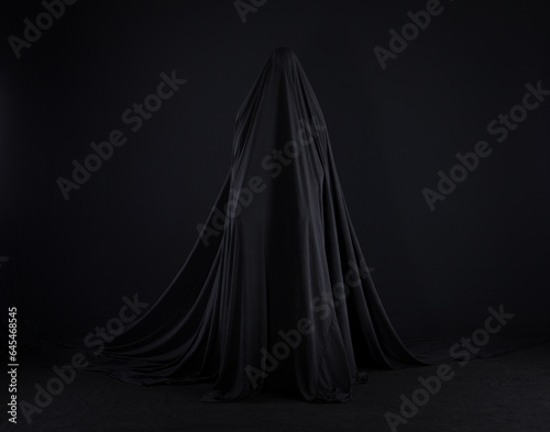 witch in a black cloak on a black background