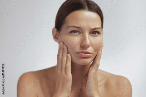 Concept photo of aging. Checking of face skin. Portrait of a worried Asian woman. Beauty treatments and lifting. passing youth. Aging and rejuvenation process. High-quality photo