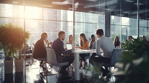 Business professionals collaborating in a lively office environment, engaged in a productive meeting while working together at a table with laptops, showcasing teamwork and positive interactions