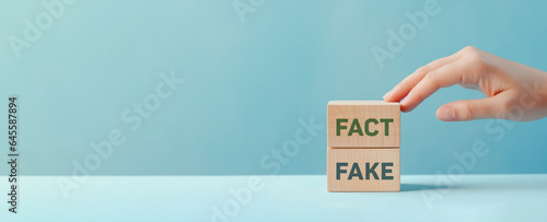 Fact or Fake concept, Hand choose fact wood cube on pastel blue background, April fools day