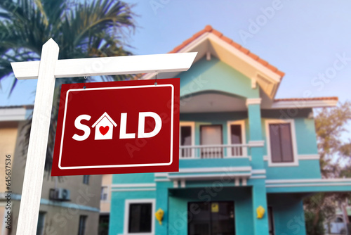 A homey sold sign in front of a quaint two story house. Prime real estate advertised as purchased.