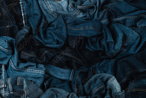 Denim background. Variety of crumpled blue jeans. Top view to stack of jeans denim