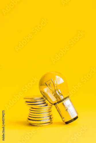 A lamp and money on a yellow background with copy space. Price for electricity concept. Expensive electricity cost.