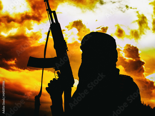 Muslim militant with rifle in the desert on sunset with AK rifle