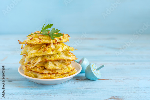 Cabbage fritters or latkes for Jewish holiday Hanukkah on blue wooden background with copy space.
