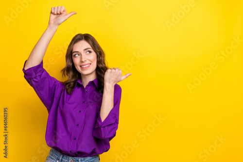 Portrait of gorgeous cheerful lady look indicate thumb fingers empty space ad isolated on yellow color background