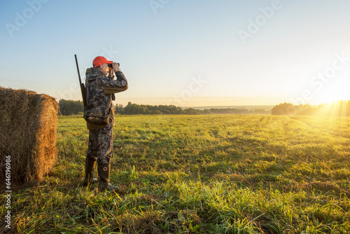 Male with a gun looking in binoculars. Hunter man.