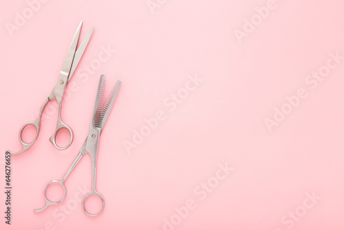 New professional hair scissors and thinning shears on light pink table background. Pastel color. Closeup. Top down view. Empty place for text.