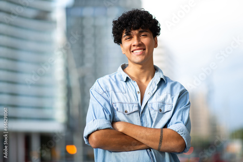 smiling young guy in city with arms crossed