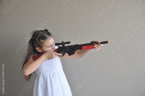 Menina brincando com arma de fogo de brinquedo, tiro ao alvo 