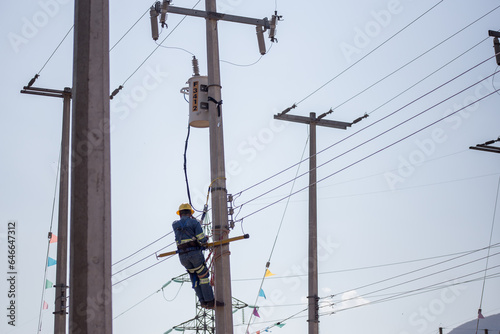 Liniero electricista ingeniero trabajando trepando un poste para reparar y dar mantenimiento a una linea eléctrica y un transformador 