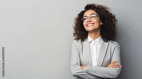 Happy youthful confident professional business woman, pretty trendy female executive looking at camera, standing arms crossed on gray background