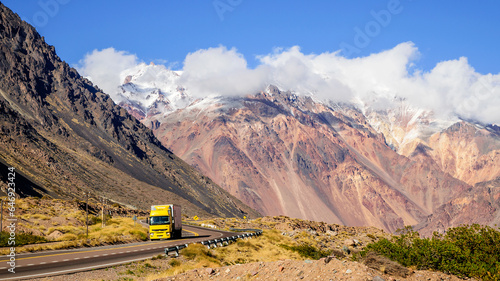 Vemos hermoso camino a chile , camión amarillo de transporte cruzando y transportando desde Chile a Argentina , entre la bella cordillera de Los Andes.