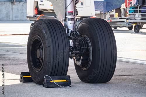 Detailed view of commercial aircraft main landing gear. Airplane wheels with tires on airport runway.