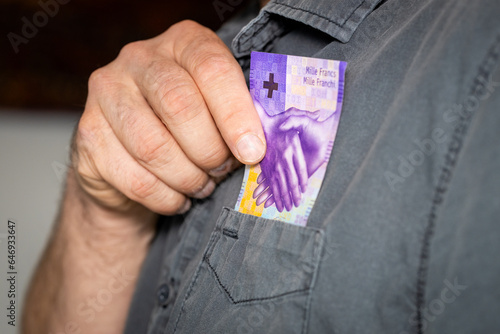 The man takes a thousand Swiss francs out of his shirts pocket, the highest denomination of paper money in Switzerland, business concept, 1000 francs banknote