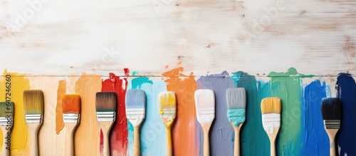 Bird s eye view of a paintbrush and various color samples on a white wooden background