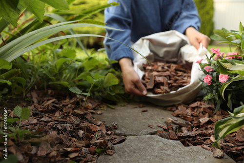 Woman holding sack with bark chips in garden, selective focus