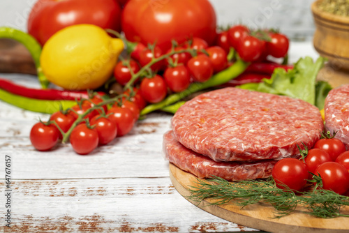 Raw hamburger patties on wood background. Raw veal hamburger patties with herbs and spices. Copy space. Free space for text