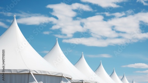 Row of white tent tops under a blue sky background.