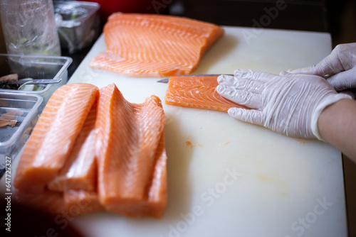 Chef cuts salmon and uses it to make sushi and sashimi on the restaurant.