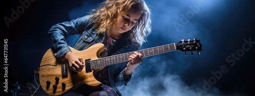 Teenage girl playing guitar on dark background