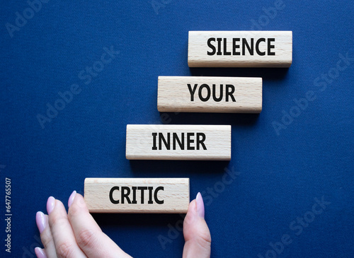 Silence your inner critic symbol. Wooden blocks with words Silence your inner critic. Beautiful deep blue background. Businessman hand. Business and Silence your inner critic concept. Copy space.