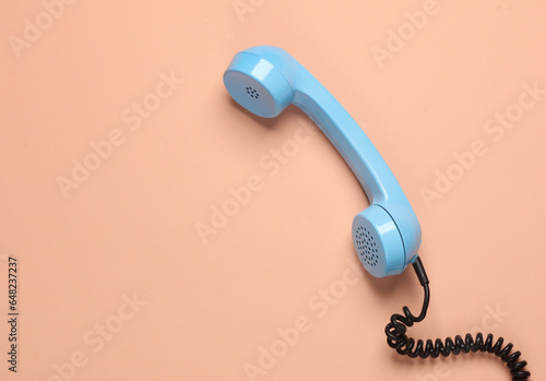 Retro blue telephone receiver on a pink background