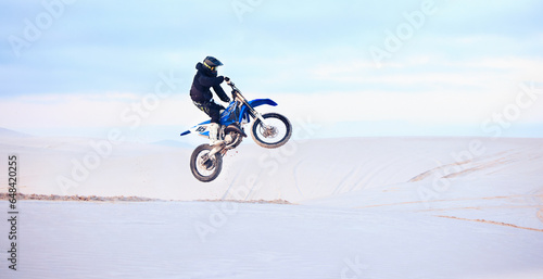 Desert, jump or person driving motorcycle for action, adventure or fitness with performance or adrenaline. Sand, risk or sports athlete on motorbike on dunes for training, exercise or race challenge