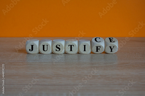 Turned wooden cubes and changes the word justify to justice. Beautiful wooden table, orange background. Copy space.