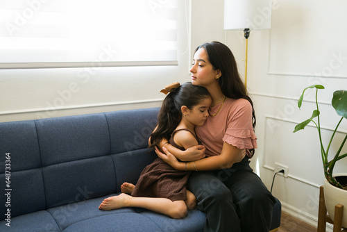 Sick kid hugging her mom feeling ill and sad