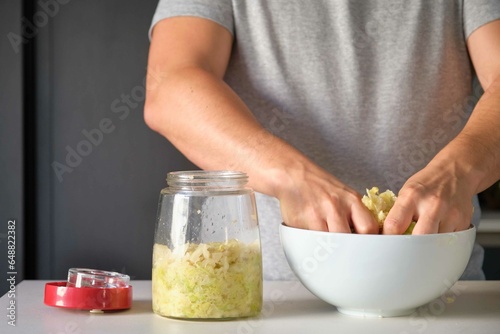 Unrecognizable man preparing homemade sauerkraut or fermented cabbage.