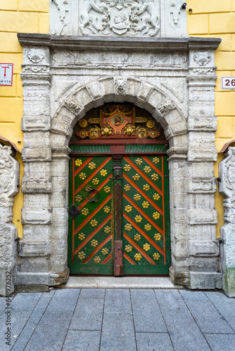 Door of the house of the Blackheads in the city of Tallinn, on a cloudy day. Green door with yellow details.