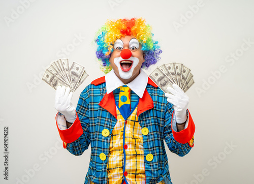 Mr Clown. Portrait of Funny face Clown man in colorful uniform standing holding a lot of money for gambling. Happy expression male bozo in various pose on isolated background.