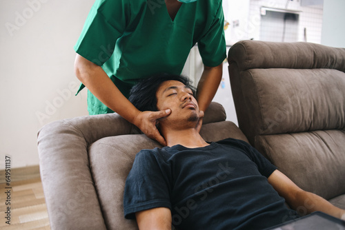 Male physiotherapist or masseur giving a neck massage to a young man lying on sofa at clinic 