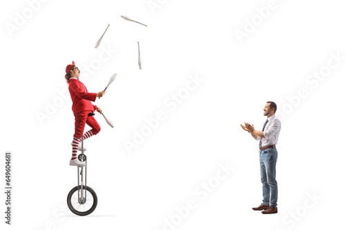 Man giving applause to an acrobat riding a giraffe unicycle and juggling