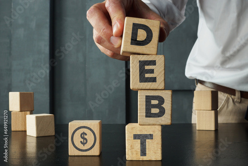 Wooden blocks with the word debt and the image of dollars. Payment of taxes and of debt to the state. Concept of financial crisis and problems. Risk management. Debt exemption