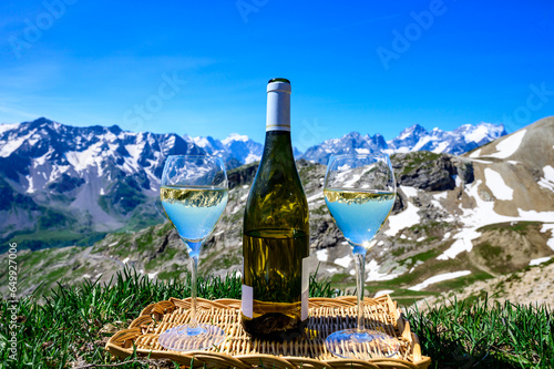 Glass and bottle of dry white Roussette de Savoie or Vin de Savoie wine from Savoy region served on Col du Galibier border Savoy region, France, view on Alpes mountains