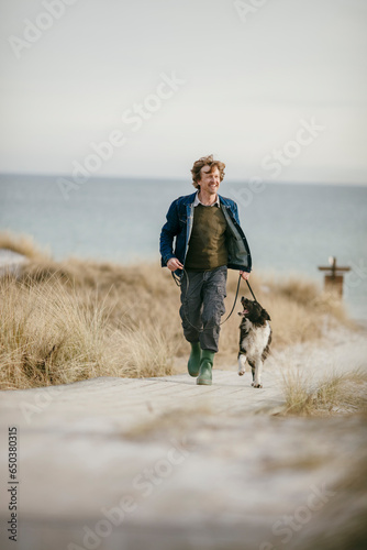 Middle aged Caucasian man walking his border collie on the beach
