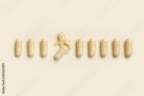 Medical capsules in a line with one opened to show beige powder top view. Dietary supplements