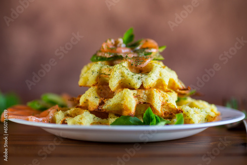 Cooked potato waffles with lightly salted red fish and herbs in a plate.