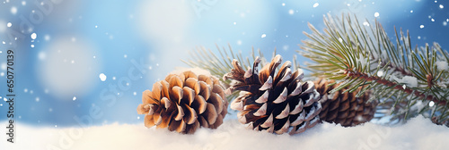 Christmas snowy winter holiday celebration greeting card - Closeup of pine branch with pine cones and snow, defocused blurred background with blue sky, bokeh lights, and snowflakes