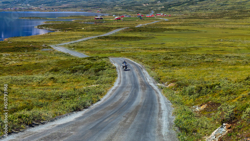 Famous Jotunheimvegen road in Jotunheimen national park through Innlandet in Norway mountains area with lonely motorcyclist.