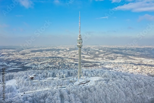 Aerial view of lush snow-covered woods with Avala Tower in the background. Beli Potok, Serbia.