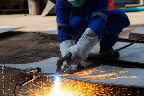 Worker cutting steel plate with Plasma Cutting process. Plasma cutting is a process that cuts through electrically conductive materials by means of an accelerated jet of hot plasma.