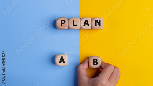 The hand of a businessman choosing business plan B out of two options on a yellow and blue background. Business strategy and decisions concept.