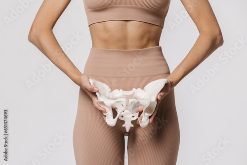 Close-up of the female pelvis in the hands of an athletic, healthy woman. Gynecology, women's healthcare and medicine and healthy body concept.